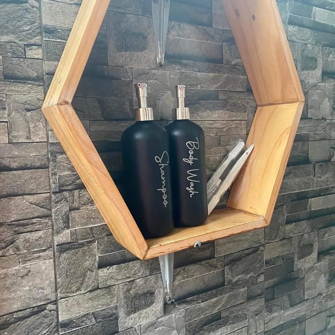 Shampoo and body wash bottles on a hexagonal wooden shelf against a stone wall