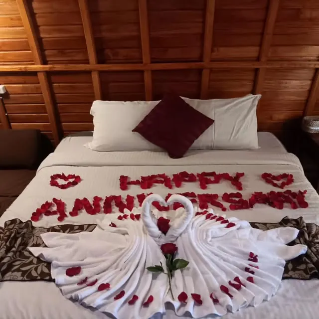 Inside a lumbung cottage: a made-up double bed under the curved timber ceiling